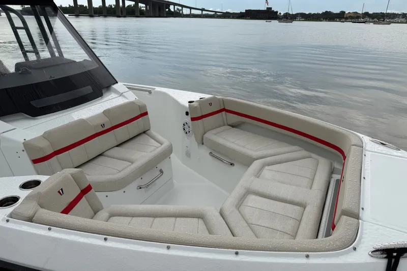 Slide: The Image of 2027 Wellcraft 28 T-Top boat interior with cushioned seating, docked by a calm waterfront. - 11