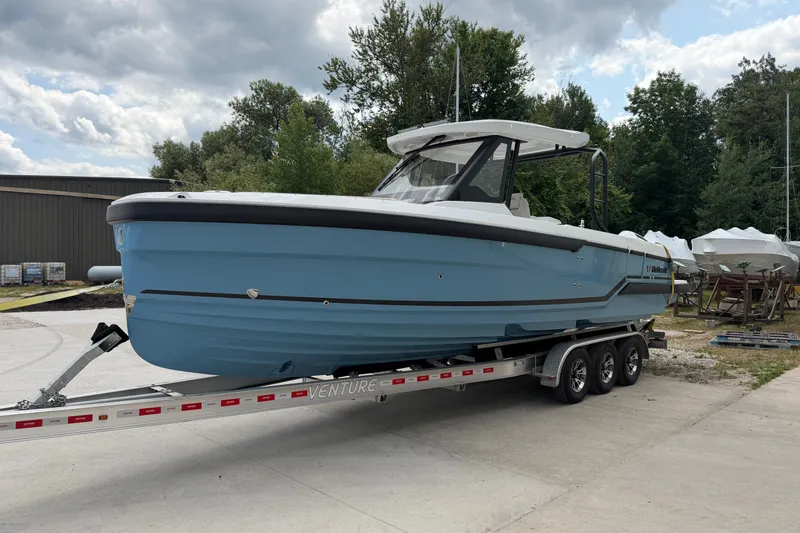 Slide: The Image of 2027 Wellcraft 28 T-Top boat on trailer, parked outdoors under cloudy sky. - 0
