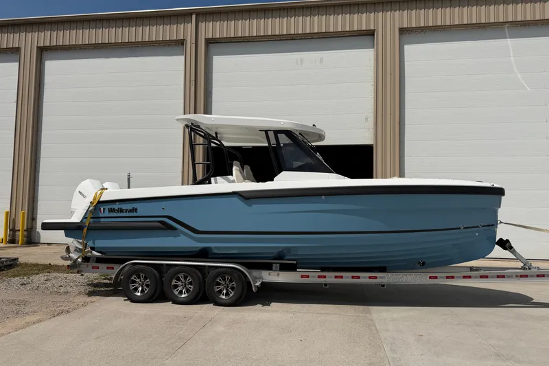 Slide: The Image of 2027 Wellcraft 28 T-Top boat on trailer, parked outside a warehouse. - 1