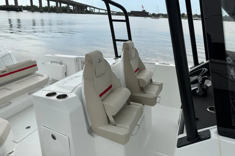 Slide: The Image of 2027 Wellcraft 28 T-Top boat interior with beige seating and cup holders on a calm waterway. - 10