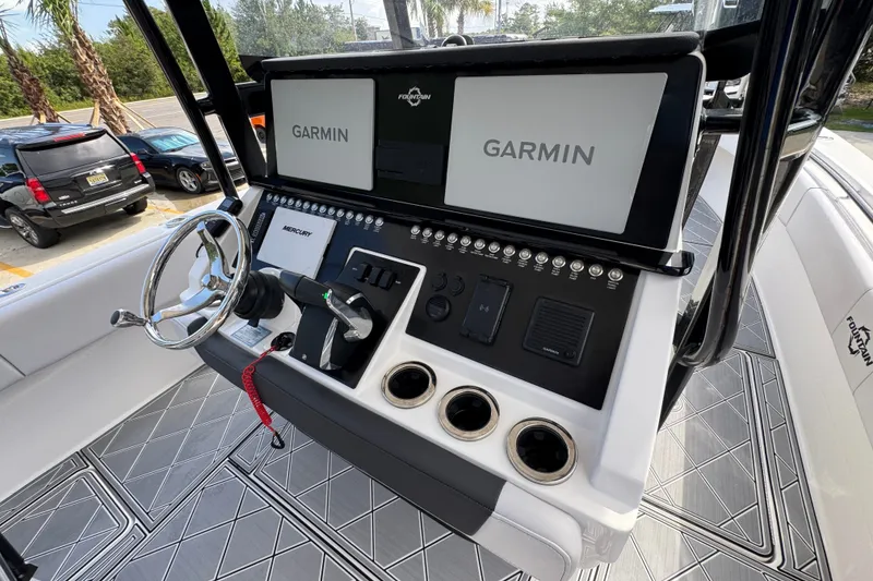 Slide: The Image of 2024 Fountain 34 Center Console boat dashboard with Garmin displays and Mercury controls. - 34