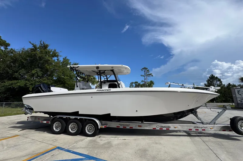 Slide: The Image of 2024 Fountain 34 Center Console boat on trailer, parked outdoors under a blue sky. - 11