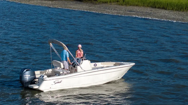 Slide: The Image of A 2027 Scout 188 Sportfish boat cruising on calm waters near a green shoreline. - 39