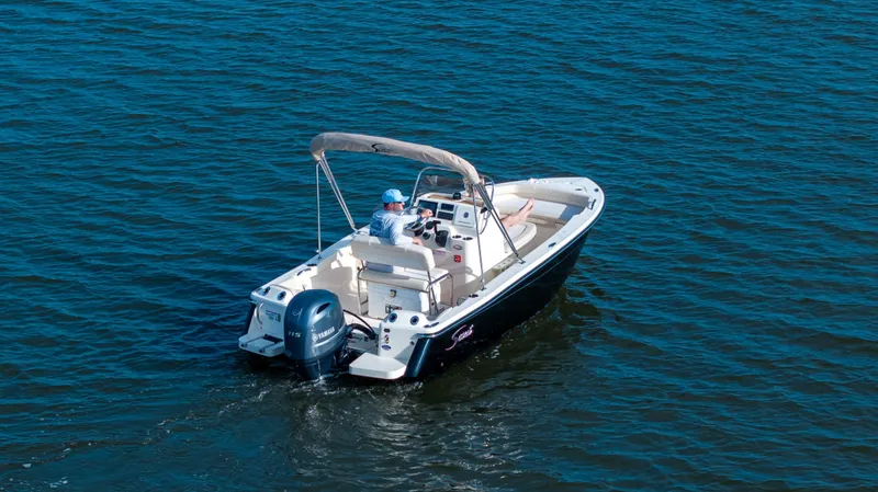 Slide: The Image of Scout 188 Sportfish 2027 on calm water with outboard motor and sunshade. - 49