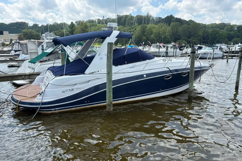 Slide: The Image of 2005 Four Winns 348 Vista boat docked at a marina under a cloudy sky. - 1