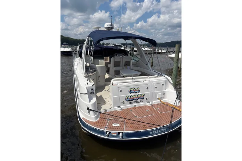 Slide: The Image of 2005 Four Winns 348 Vista boat docked, featuring spacious deck and seating under a blue canopy. - 6