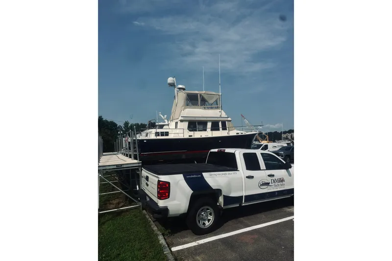 Slide: The Image of 1996 Sabreline 36 Sedan yacht on trailer beside branded truck in marina. - 2