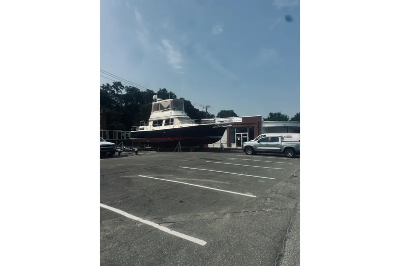 Slide: The Image of 1996 Sabreline 36 Sedan boat on display outside a building, with parked vehicles nearby. - 108