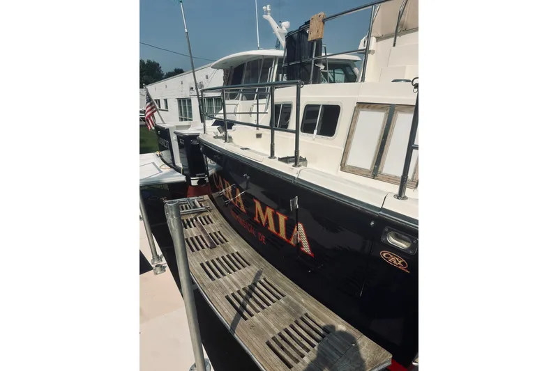 Slide: The Image of 1996 Sabreline 36 Sedan yacht docked, featuring sleek design and American flag. - 9