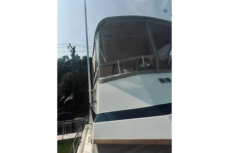 Slide: The Image of 1996 Sabreline 36 Sedan boat with covered upper deck, docked near trees and flag. - 20