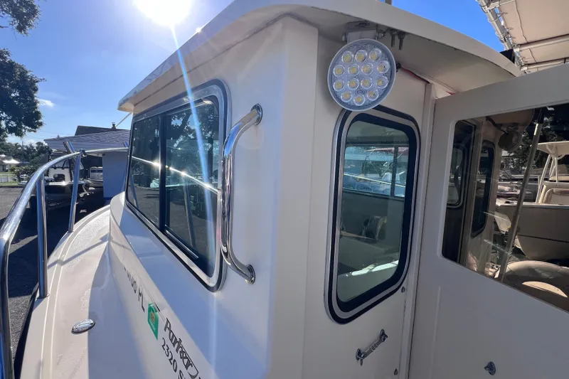 Slide: The Image of 2012 Parker 2320 SL Sport Cabin boat exterior with windows and railing in sunlight. - 19