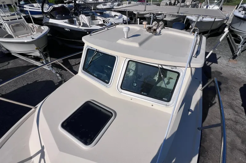 Slide: The Image of 2012 Parker 2320 SL Sport Cabin boat, docked among other vessels, showcasing its cabin and deck. - 23