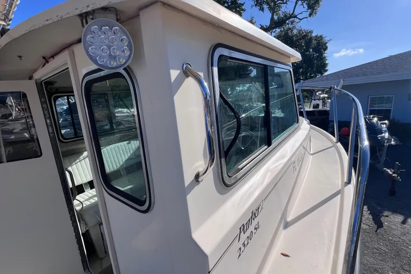 Slide: The Image of 2012 Parker 2320 SL Sport Cabin boat exterior with windows and railing in sunlight. - 20