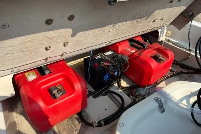 Slide: The Image of 1988 Boston Whaler 150 Super Sport boat with red fuel tanks and battery setup. - 12