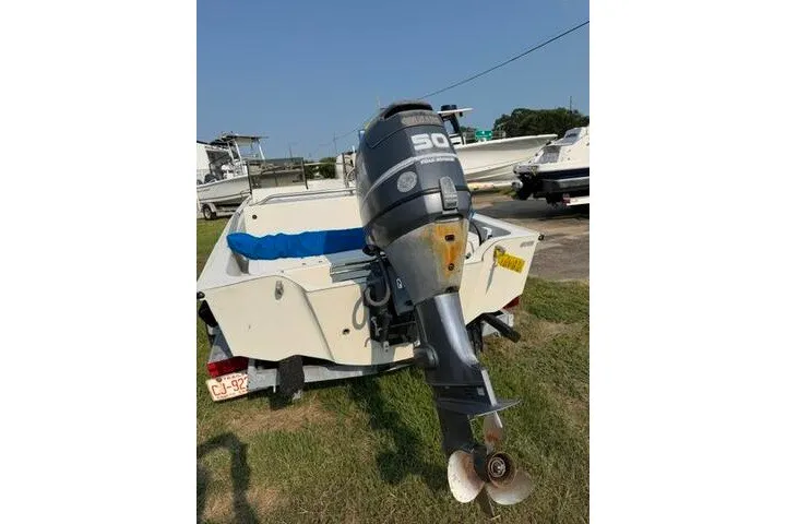 Slide: The Image of 1988 Boston Whaler 150 Super Sport with outboard motor, parked on grass. - 11