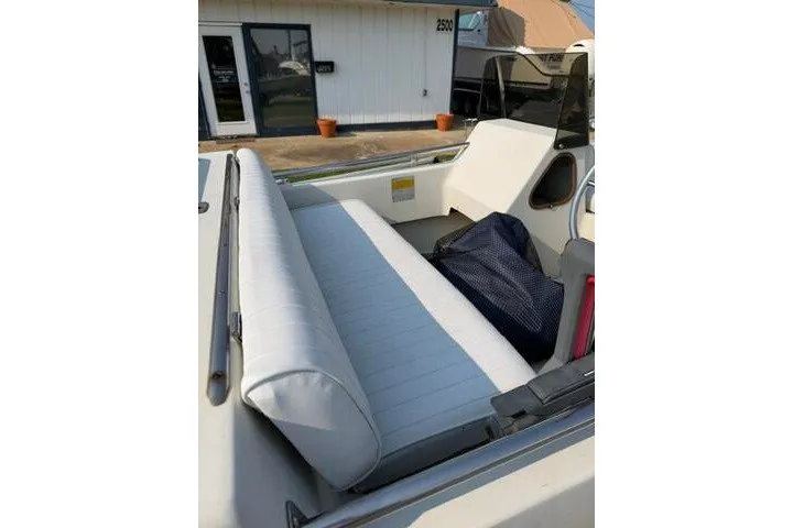 Slide: The Image of 1988 Boston Whaler 150 Super Sport boat interior with white seating and storage area. - 15
