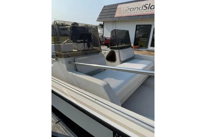 Slide: The Image of 1988 Boston Whaler 150 Super Sport boat with white seating, parked near a building. - 18