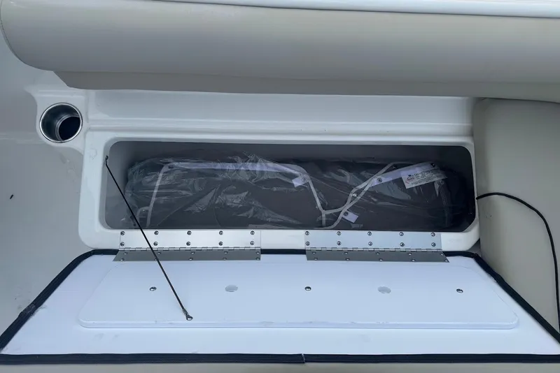 Slide: The Image of Storage compartment in a 2027 Key West 203 DFS boat, featuring a hinged lid and cup holder. - 12