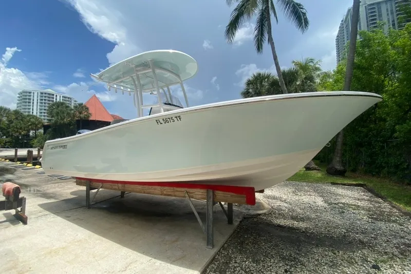 The Image of 2022 Sportsman Open 232 Center Console boat on display, surrounded by palm trees and buildings. - 0