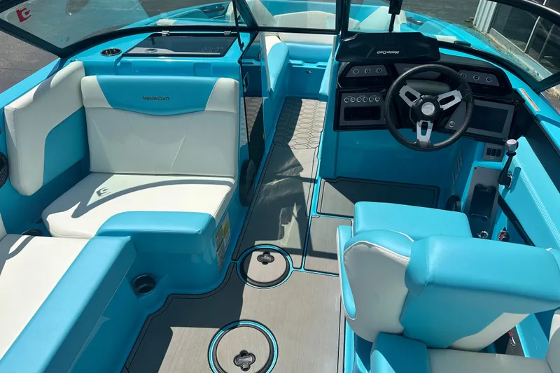 Slide: The Image of 2024 MasterCraft NXT22 boat interior with blue and white seating and modern dashboard. - 9