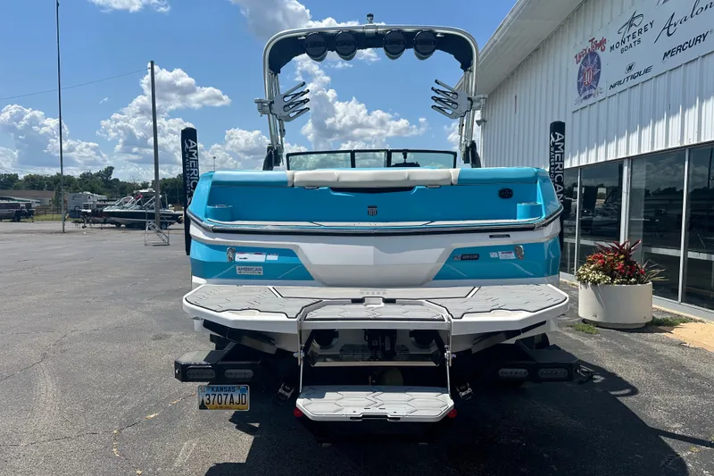Slide: The Image of 2024 MasterCraft NXT22 boat, blue and white, parked outside a dealership under a sunny sky. - 4