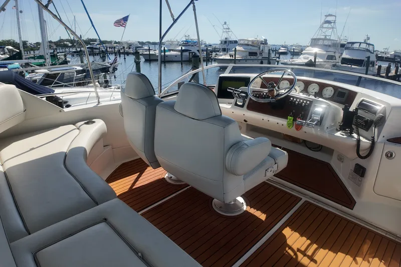 The Image of 2006 Silverton 35 Motor Yacht helm with leather seating and wooden deck at marina. - 0