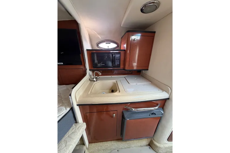 Slide: The Image of 2005 Sea Ray Sundancer 280 interior kitchen with sink, microwave, and storage cabinets. - 27