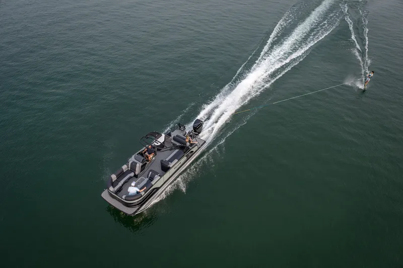 Slide: The Image of 2026 Tahoe Pontoon Grand Tahoe LTD Cruise towing a water skier on a serene lake. - 17