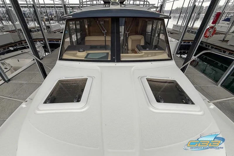 Slide: The Image of 2013 Cutwater C-28 boat docked, featuring a spacious deck and cabin windows. - 63