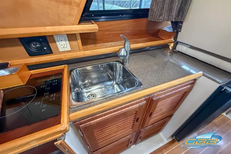 Slide: The Image of 2013 Cutwater C-28 boat kitchen with sink, stovetop, and wooden cabinetry. - 32