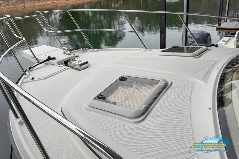 Slide: The Image of 2013 Cutwater C-28 boat deck with hatches and railing, docked by calm water. - 67