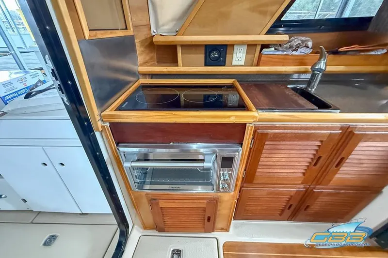 Slide: The Image of 2013 Cutwater C-28 boat kitchen with stove, oven, and wooden cabinetry. - 22