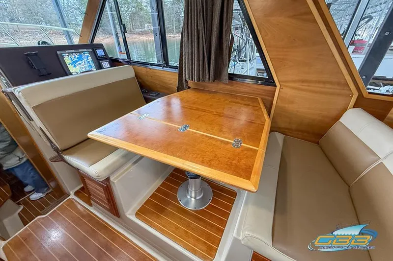 Slide: The Image of 2013 Cutwater C-28 interior with wooden table, cushioned seating, and navigation equipment. - 56