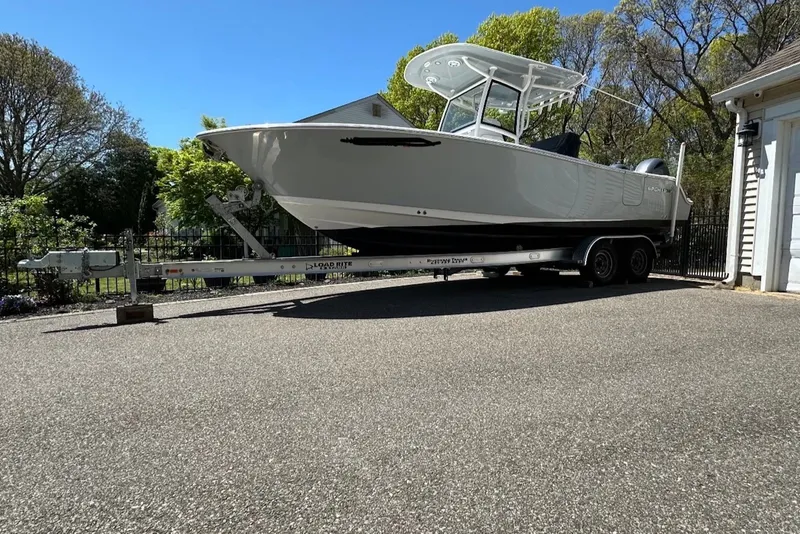 The Image of 2021 Sportsman Open 252 Center Console boat on trailer in driveway. - 0