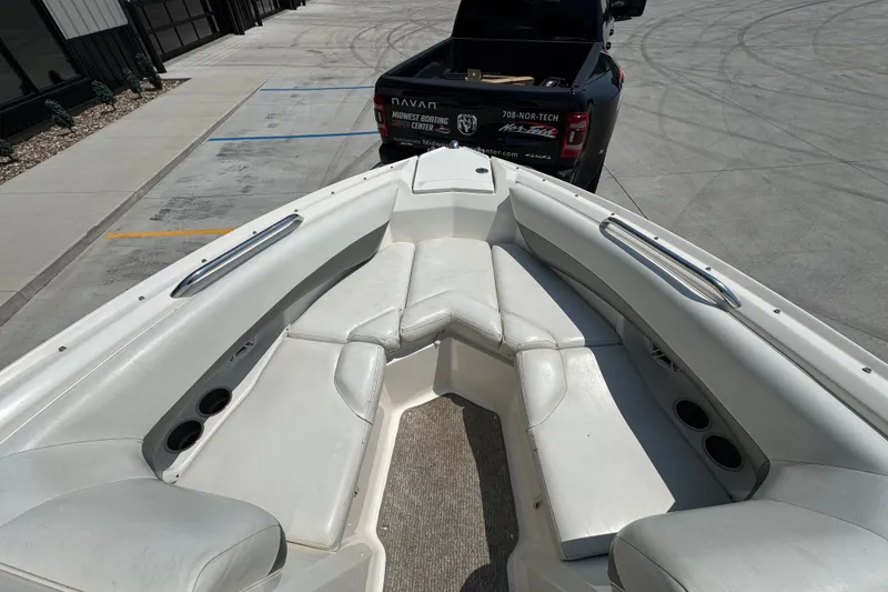 Slide: The Image of 2008 Larson LXi 228 boat interior with white seating, parked near a black truck. - 15