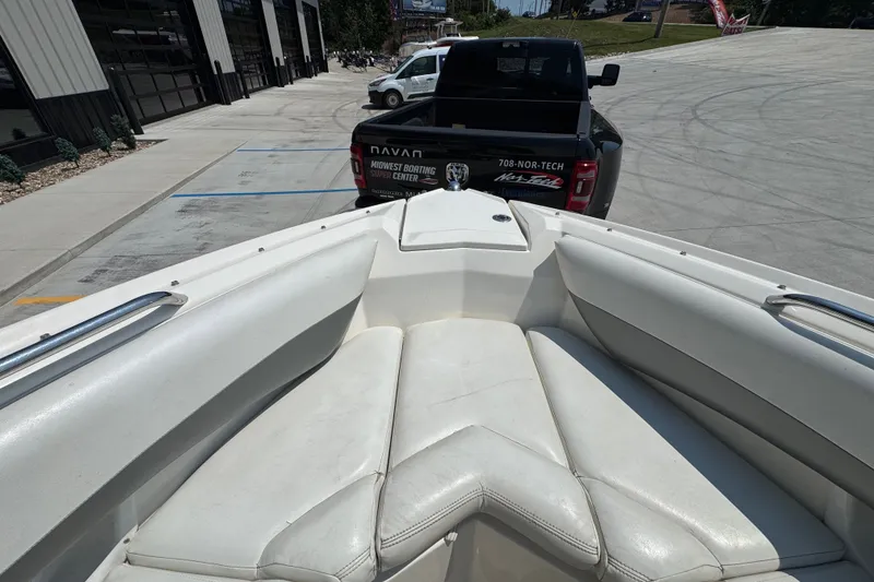 Slide: The Image of 2008 Larson LXi 228 boat interior with white seating, parked near a black truck. - 18