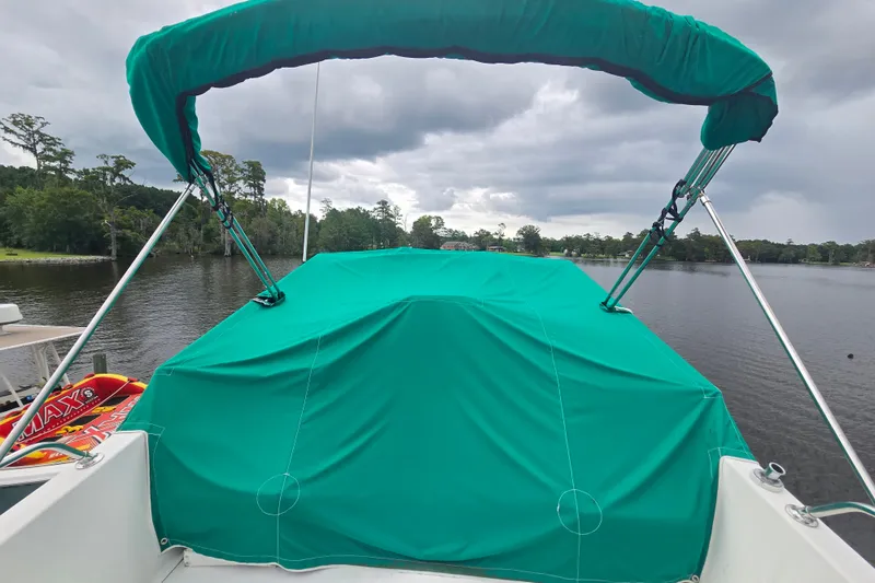 Slide: The Image of 1983 Atlantic 30 LRC boat with green canopy on a calm lake. - 7