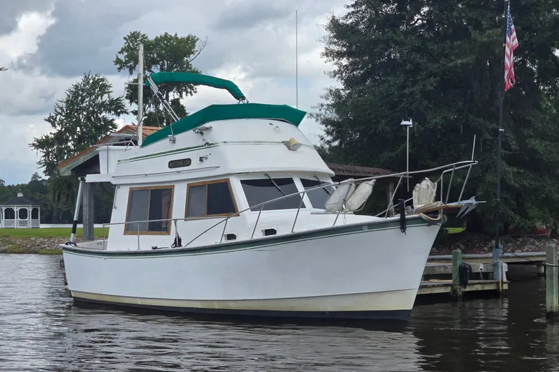 The Image of 1983 Atlantic 30 LRC boat docked on a calm river under cloudy skies. - 1