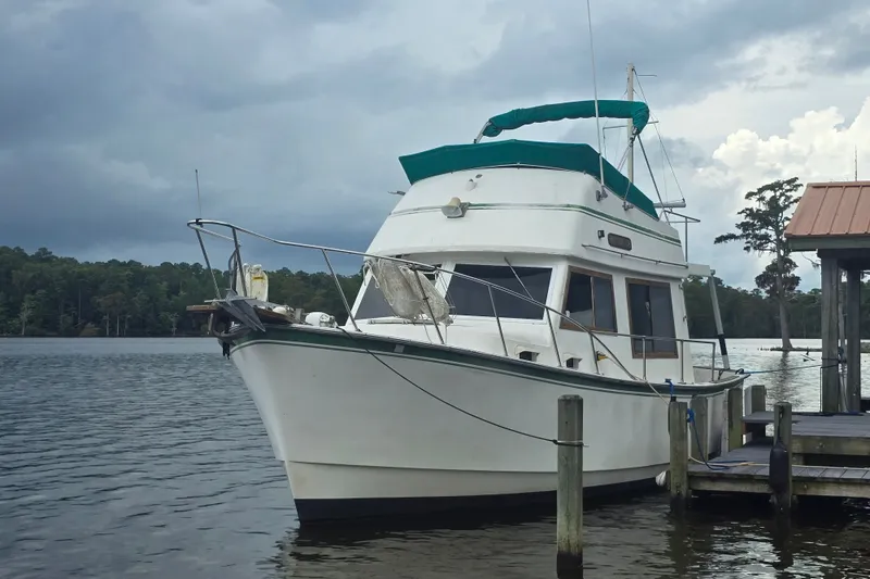 Slide: The Image of 1983 Atlantic 30 LRC boat docked on a serene lake under cloudy skies. - 2