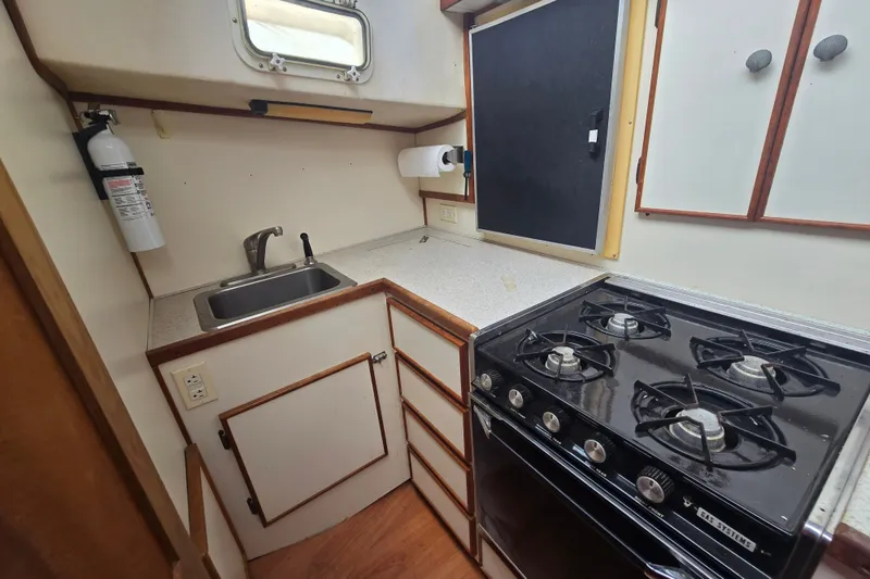 Slide: The Image of Compact kitchen in 1983 Atlantic 30 LRC boat with stove, sink, and storage cabinets. - 13