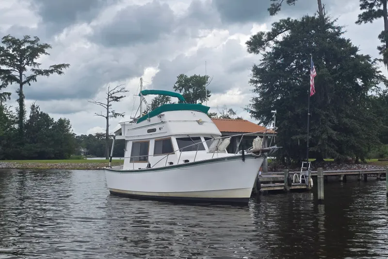 Slide: The Image of 1983 Atlantic 30 LRC boat docked on a calm lake under cloudy skies. - 5