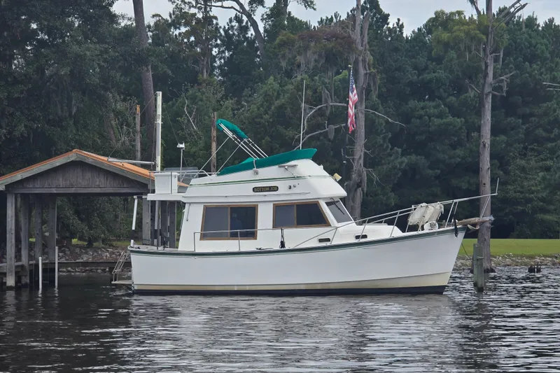 Slide: The Image of 1983 Atlantic 30 LRC boat docked by a wooded shoreline with an American flag. - 4