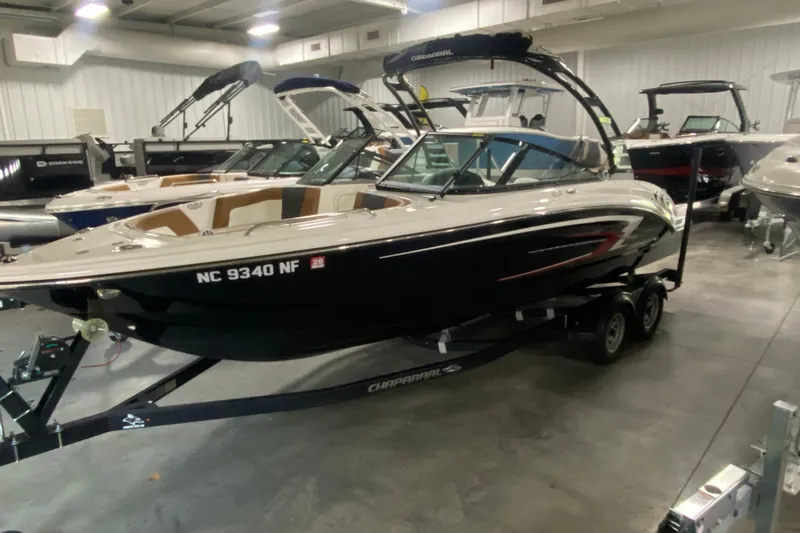 The Image of 2025 Chaparral 23 SSi boat on trailer in showroom, sleek design, black exterior. - 0