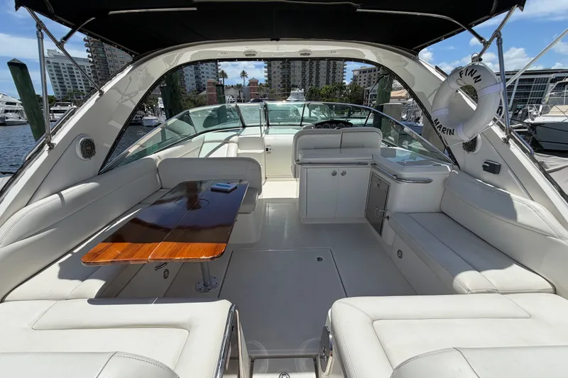 Slide: The Image of 2015 Sea Ray 370 Venture yacht interior with seating, table, and helm in marina setting. - 16