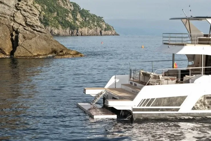 Slide: The Image of Aventura 56 Motor Yacht 2026 near rocky coastline, calm sea, and clear sky. - 8
