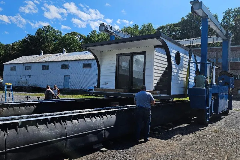 Slide: The Image of Modern 2026 East Coast Houseboats Cayuga model being constructed outdoors under blue sky. - 15