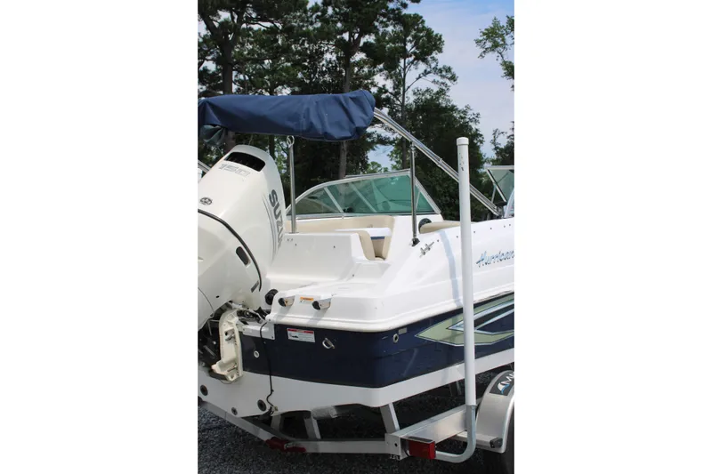 Slide: The Image of 2020 Hurricane SunDeck 187 OB boat with Suzuki outboard motor, parked on a trailer. - 23