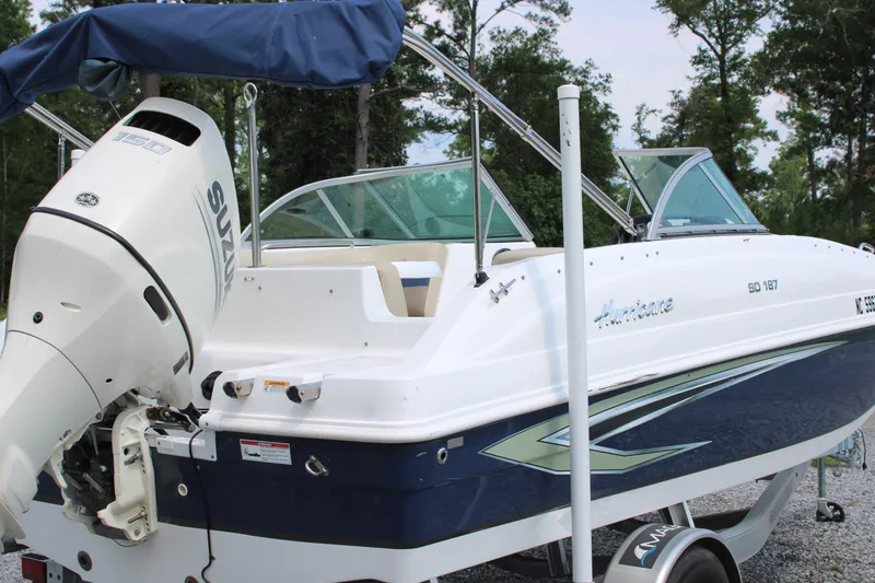 Slide: The Image of 2020 Hurricane SunDeck 187 OB boat with Suzuki outboard motor, parked on a trailer. - 24