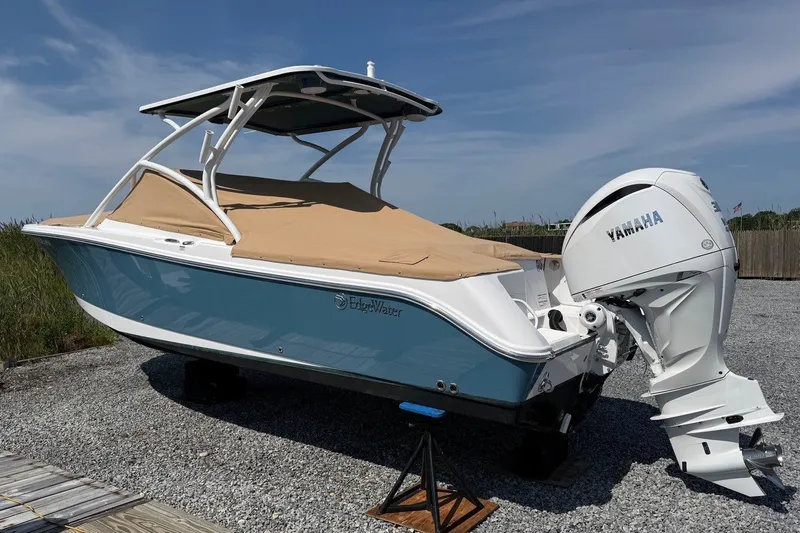 Slide: The Image of 2025 Edgewater 248CX Crossover boat with Yamaha engine, covered and parked on gravel. - 1