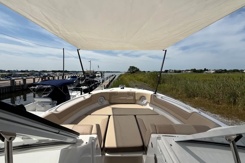 Slide: The Image of 2025 Edgewater 248CX Crossover boat with canopy, docked near lush greenery and calm waters. - 32